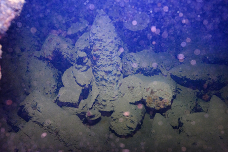 3/9/2023 - Dive 12 - Kansho Maru<br>In another hold, we peeked through a small-ish hole to see stacks of large artillery shells jumbled about.